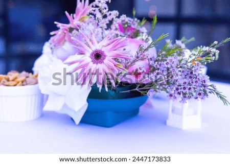 A chic party table setting with snack food with pink flowers and tea lamp with cheese puffs (Cheetos Brand) crisps and pretzels with an informal feel. 