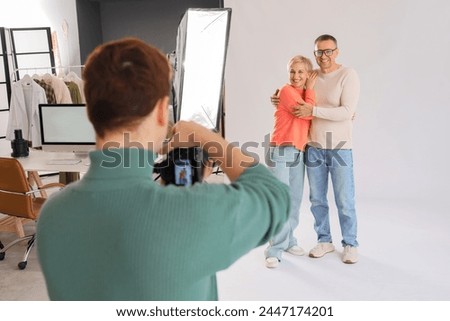 Male photographer taking picture of mature couple in studio