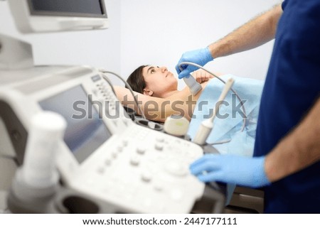 Mammologist doctor examines a woman breasts and lymph nodes using ultrasound. Mammography and ultrasound scanning are main methods of instrumental diagnosis of mammary glands. Breast cancer awareness Royalty-Free Stock Photo #2447177111