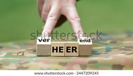 Hand turns cube and changes the German word 'Heer' (army) to 'verheerend' (disastrous). Symbol for the disastrous situation of the German army. Royalty-Free Stock Photo #2447209245