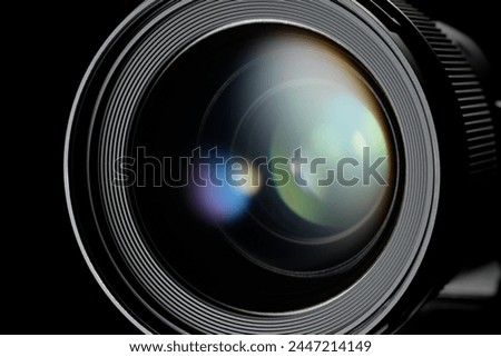 Photo or video camera lens with light reflections close-up on the black background.