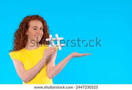 beautiful woman in yellow summer dress  holding sign hashtag in her hand on blue  background with copy space. social media, blogging and viral topics on internet concept