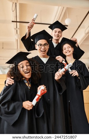 A diverse group of students in graduation gowns and academic caps smiling for a picture to commemorate their educational milestone.