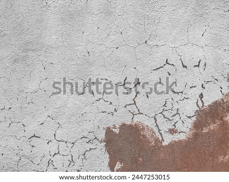 A wall marred by numerous cracks and holes, showing signs of wear and tear, adding character to its weathered appearance.