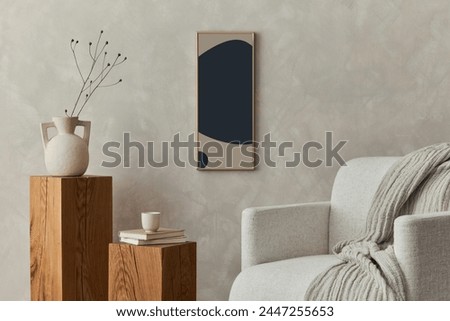 Stylish composition of modern cozy living room interior with structure painting,  beige armchair, wooden cubes and personal accessories. Neutral creative wall. Template.