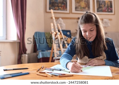 Front view portrait of teen girl with Williams syndrome drawing picture with crayons in art studio copy space