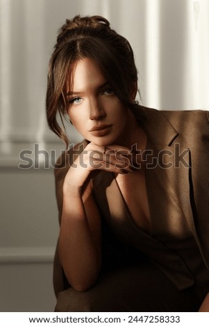 Portrait of a gentle girl in a brown suit. Brunette with blue eyes. Trendy studio shooting of the girl model.
