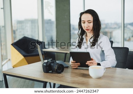 Young female photographer working on a tablet, retouching photos on a portable tablet. Photo processing on a laptop.