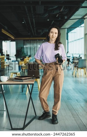 Photographer female student with coffee using laptop working with photography in coworking space, young freelancer working remotely with web design