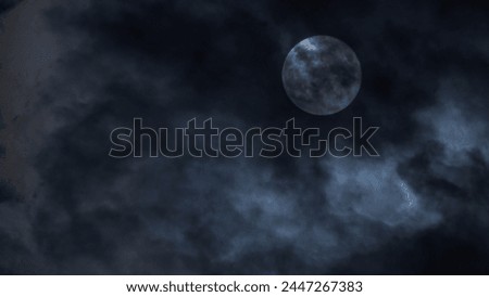 The moon peeks through clouds, casting an eerie blue glow in the night sky