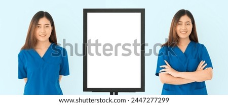 Two women in blue scrubs stand in front of a white board. One of the women is smiling.