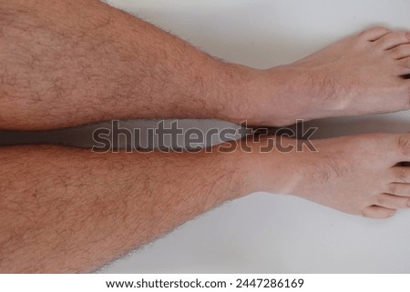 hairy male legs on a white background, increased hairiness of the legs, lack of depilation, unshaven legs 