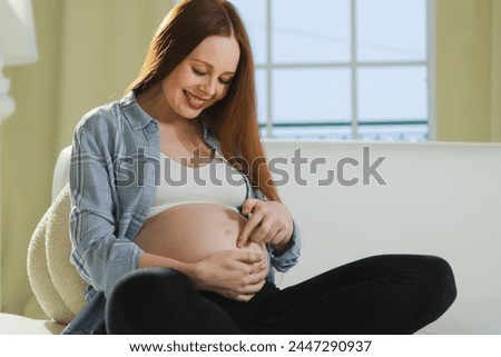 Pregnancy motherhood people expectation future. Pregnant woman touching big belly sitting on couch at home. Girl hugging her tummy enjoying pregnancy. Maternity tenderness parenthood new life concept Royalty-Free Stock Photo #2447290937