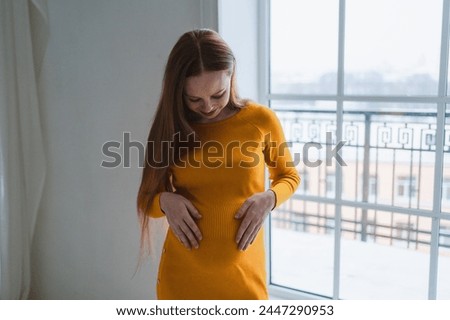 Pregnancy motherhood people expectation future. Pregnant woman with big belly standing near window at home. Girl hugging her tummy enjoying pregnancy. Maternity tenderness parenthood new life concept Royalty-Free Stock Photo #2447290953