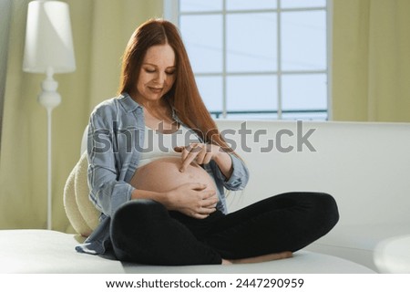 Pregnancy motherhood people expectation future. Pregnant woman touching big belly sitting on couch at home. Girl hugging her tummy enjoying pregnancy. Maternity tenderness parenthood new life concept Royalty-Free Stock Photo #2447290959