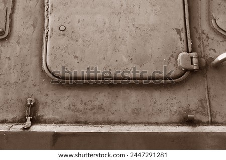 The side of an armored personnel carrier with a hatch.  Close-up photograph of an armored vehicle's metal armored hatch.