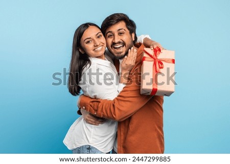 Eastern man and woman share a happy moment as they embrace with a gift box, symbolizing giving and affection