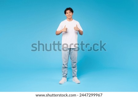 Full body portrait of a young asian guy giving two thumbs up, expressing approval and confidence on blue background Royalty-Free Stock Photo #2447299967