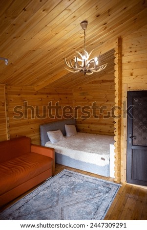 The cabins interior is paneled with wood and furnished with a bed, sofa, and armoire. A bearskin rug adds a touch of warmth to the space. Royalty-Free Stock Photo #2447309291