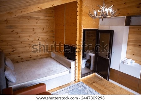 The cabins interior is paneled with wood and furnished with a bed, sofa, and armoire. A bearskin rug adds a touch of warmth to the space. Royalty-Free Stock Photo #2447309293