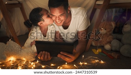 Happy, tablet and child kiss father in a tent house streaming internet video, show or movie online and bonding at night. Dark, digital and parent or dad relax with kid watching comedy in the evening