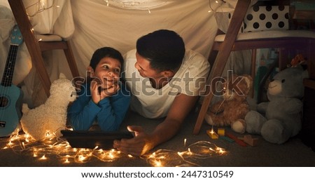 Dad and son at night on tablet in tent watching movies, online games and cartoon with fairy lights. Happy family, blanket and father with boy in bedroom on digital tech for bonding, relax and love