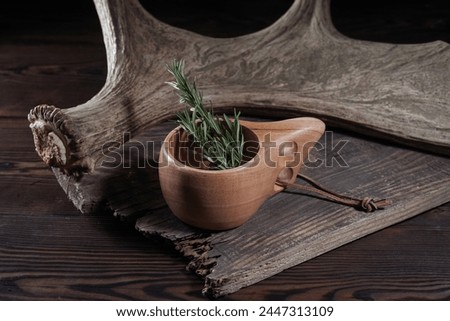 Scandinavian wooden mug. Mug and spices. Rosehip and pine needles. Moose horn on the background. Royalty-Free Stock Photo #2447313109