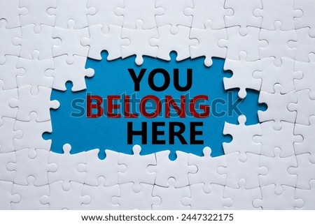 You belong here symbol. White puzzle with words You belong here. Beautiful blue background. Business and You belong here concept. Copy space.