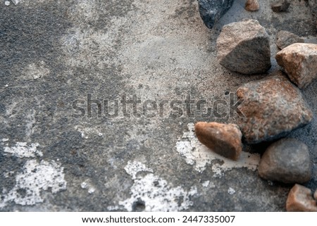 Granite stones lie on a cement screed. Large granite stones lie chaotically, top view. Granite stones next to each other.