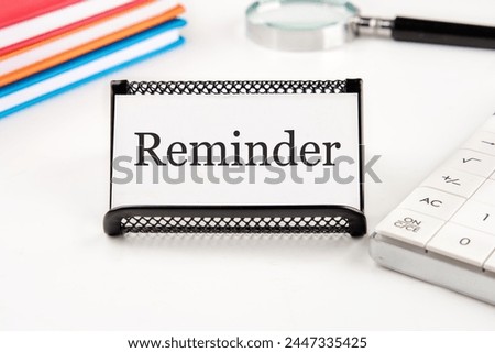 reminder word on a white business card on a table with office supplies