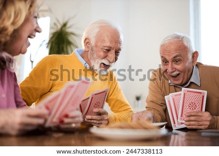 Group of happy seniors having fun while playing cards at home.