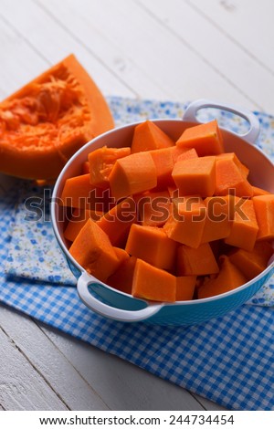 Fresh raw pumpkin in bowl on wooden background. Selective focus.