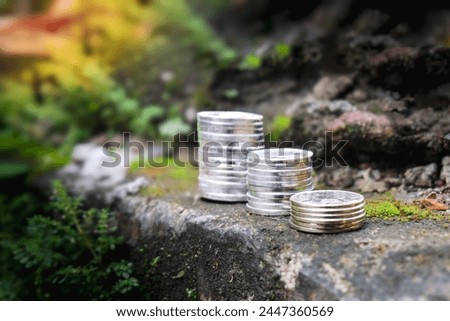 financial illustration, stack of rupiah currency coins from Indonesia with buildings and nature in the background