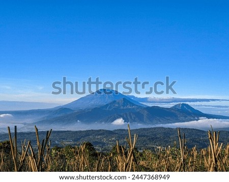 This is a view of a group of mountains in Central Java, Indonesia. In the picture there are Mount Telomoyo and Mount Merbabu. This moment was taken in the morning with clear weather and blue skies
