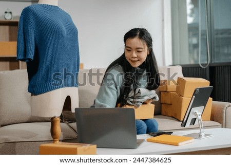 Successful fashion designer. Attractive woman with smile while standing in workshop. Beautiful owner woman working and holds tablet, laptop and smartphone in studio.