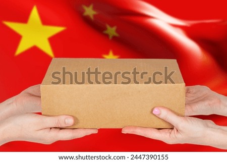Parcel with Chinese flag. Cardboard box in hands. Trade exchange with China concept. Metaphor for ordering goods in PRC. Sending parcels from China. Delivery from people republic of China Royalty-Free Stock Photo #2447390155