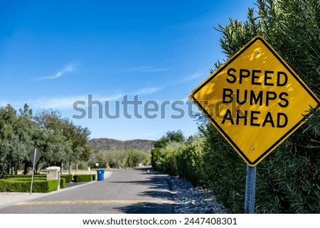 Selective focus on a yellow speed bump sign with a defocused road in the background.