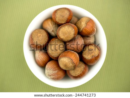 Bowl of hazelnuts against textured green background