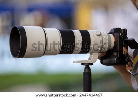 Symbol image sports photographer, sports photography: Close-up of a large telephoto lens in a football stadium