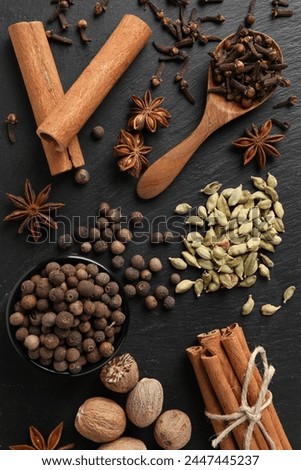 Different spices on black textured table, flat lay