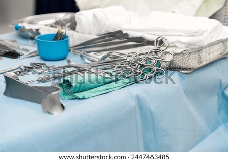 Sterile surgical instruments and tools including scalpels, scissors, forceps and tweezers arranged on a table for a surgery, Sterilized surgical instruments on the blue or green wrap	 Royalty-Free Stock Photo #2447463485