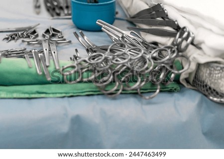 Sterile surgical instruments and tools including scalpels, scissors, forceps and tweezers arranged on a table for a surgery, Sterilized surgical instruments on the blue or green wrap	 Royalty-Free Stock Photo #2447463499