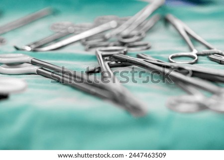 Sterile surgical instruments and tools including scalpels, scissors, forceps and tweezers arranged on a table for a surgery, Sterilized surgical instruments on the blue or green wrap	 Royalty-Free Stock Photo #2447463509