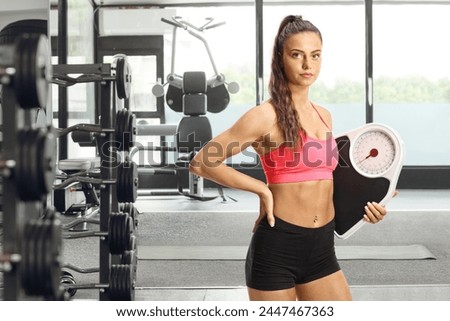 Female fitness coach holding a weight scale at a gym Royalty-Free Stock Photo #2447467363