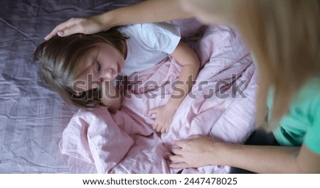 Mother stroking head of little sad girl lying in bed. Psychological problems in children concept Royalty-Free Stock Photo #2447478025