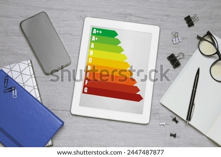 Energy efficiency rating on tablet display. Flat lay composition on table