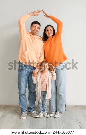 Happy family dreaming about their new house near grey wall