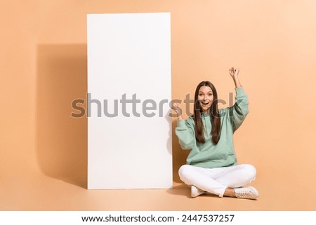 Portrait of attractive cheerful lucky girl sitting rejoicing new offer copy space isolated over beige pastel color background