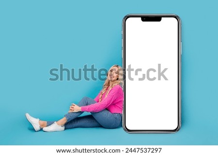 Full body length size of sitting relaxed blonde hair woman near smartphone display new web constructor isolated on blue color background