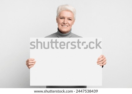 The image depicts a senior European woman holding a blank sign, ideal for custom messaging within a s3niorlife framework